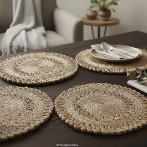 Op de afbeelding: Vier ronde, beige jute placemats met een geschulpte rand zijn gerangschikt op een donkere houten tafel. Op een placemat liggen een bord, bestek en een servet. De placemats hebben een diameter van ongeveer 33 cm.