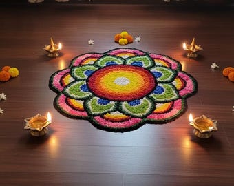 May include: A colorful floral design made of flower petals and other materials, with a yellow center and surrounded by pink, green, blue, and yellow petals. Four lit brass oil lamps and small flower arrangements surround the design on a dark wood floor.