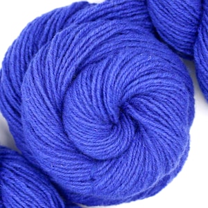 May include: Three balls of blue yarn, wound into skeins, are arranged in a row on a white background.
