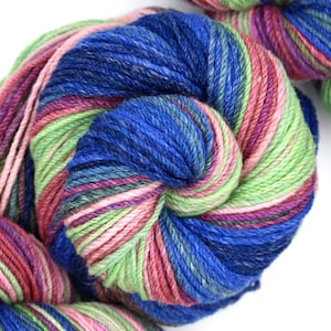 May include: A skein of yarn in a multi-coloured pattern of blue, green, pink, and purple. The yarn is wound into a ball shape.