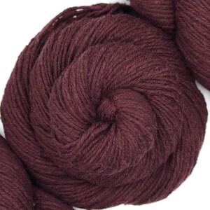 Peut inclure: Gros plan sur une pelote de fil brun foncé. Le fil est doux et moelleux, idéal pour le tricot ou le crochet.