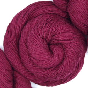 Puede incluir: Un ovillo de hilo de color burdeos oscuro, enrollado en una bola apretada.