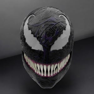 May include: A black Venom mask with white mesh eye openings and a wide, toothy grin. The mask has a textured surface with purple accents, resembling the Marvel Comics character.