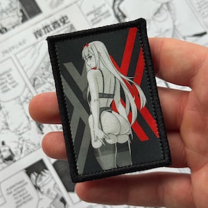 Könnte beinhalten: Ein rechteckiger Aufnäher mit einer Anime-Illustration einer Frau mit langen weißen Haaren, die Unterwäsche trägt. Der Hintergrund enthält ein rotes 'X'-Design und graue geometrische Formen. Der Aufnäher hat einen schwarzen Rand.