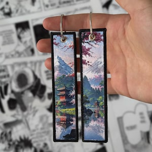 May include: Two rectangular embroidered patches with a Japanese landscape design. Each patch features a red pagoda, mountains, and cherry blossoms reflected in a lake. The patches have a black border and silver metal loops.