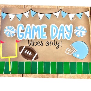 The image is a vibrant and colorful sign that reads "GAME DAY VIBES ONLY!" The sign is adorned with various football-related elements, such as a football, a cheerleader, and a football helmet, all set against a green background.