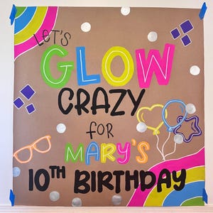 A colorful birthday sign with the text "Let's glow crazy for Mary's 10th birthday" written on it.