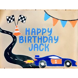 The image is a birthday banner for a child named Jack, featuring a race car, checkered flags, and a banner with the text "Happy Birthday Jack".