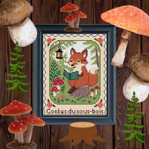 Peut inclure: Une broderie au point de croix encadrée représentant un renard lisant un livre, portant des lunettes et assis sur une souche d'arbre. Le motif comprend des champignons, une lanterne et le texte "Contes du sous-bois". Les couleurs sont marron, vert, rouge et blanc.