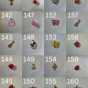 K&ouml;nnte beinhalten: Eine Sammlung von zwanzig kleinen Metallanh&auml;ngern, nummeriert von 141 bis 160, mit verschiedenen Formen wie Kreuz, Geist, Gitarre, Herz, Stern, Biene, W&uuml;rfel, Schmetterling, Kaktus, Spielkarten und Cowboyhut in verschiedenen Farben und Ausf&uuml;hrungen.