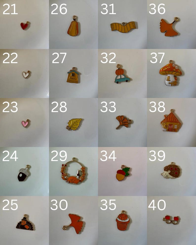 K&ouml;nnte beinhalten: Eine Sammlung von zwanzig kleinen Metallanh&auml;ngern, nummeriert von 21 bis 40, mit verschiedenen herbstlichen Motiven wie Herzen, Bl&auml;ttern, K&uuml;rbissen, H&auml;usern, Pilzen, einem Igel und einem Cupcake, jeweils mit einer kleinen &Ouml;se zur Befestigung.