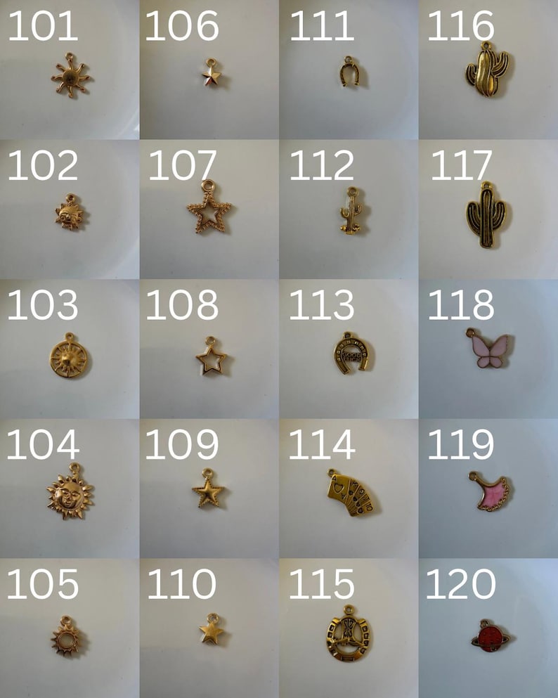 K&ouml;nnte beinhalten: Eine Sammlung von zwanzig kleinen goldfarbenen Metallanh&auml;ngern, nummeriert von 101 bis 120, mit verschiedenen Formen wie Sonnen, Sternen, Hufeisen, Kakteen, einem Schmetterling, einem F&auml;cher und einem Planeten, jeweils mit einer kleinen &Ouml;se.
