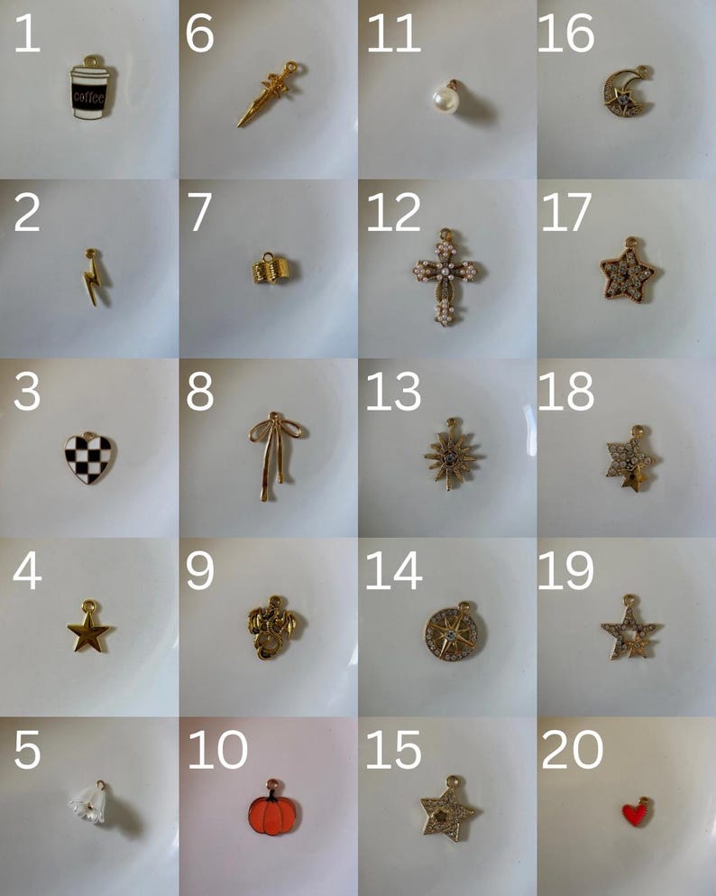 K&ouml;nnte beinhalten: Eine Sammlung von zwanzig kleinen Metallanh&auml;ngern in einem Raster, darunter Formen wie Kaffeetasse, Blitz, Schachbrett-Herz, Sterne, Schwert, Schleife, Kreuz, K&uuml;rbis und Mond, teilweise mit Strasssteinen, Emaille oder Perlen.