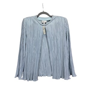 Puede incluir: Chaqueta plisada azul claro con mangas largas, colgada de una percha negra. La chaqueta tiene un cuello redondo con un ribete de cuentas. Una etiqueta de precio cuelga del cuello. La chaqueta está hecha de un material ligero.