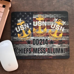 May include: Rectangular mousepad featuring a distressed American flag design with brick texture. Gold anchors with the letters "USN" are displayed. The text "DD214" and "CHIEFS MESS ALUMNI" are also visible.
