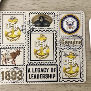 May include: Cream-colored mousepad featuring a collage of vintage-style stamps. The stamps depict anchors, a naval officer's hat, the US Navy seal, and a goat. Text includes "USN", "Genuine", "A Legacy of Leadership", and "1893".