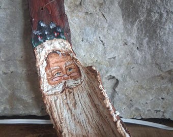 Adorno de Papá Noel de arte popular hecho a mano, tallado y pintado sobre madera flotante.