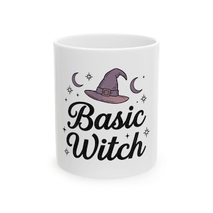 May include: A white ceramic mug featuring a graphic of a purple witch hat centered above the black text "Basic Witch". The design is surrounded by small black crescent moons and star icons, creating a simple and clear decorative pattern.