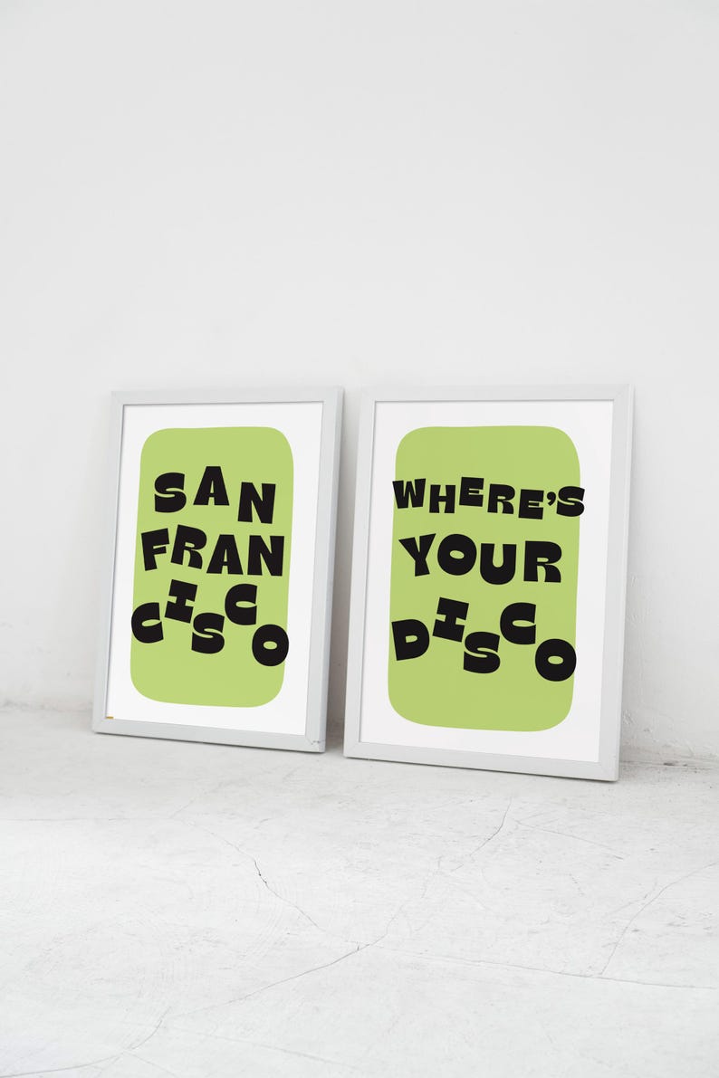May include: Two framed art prints with white frames. One print reads "SAN FRANCISCO" in black, stylized text on a light green background. The other print says "WHERE'S YOUR DISCO" in black text on a light green background.