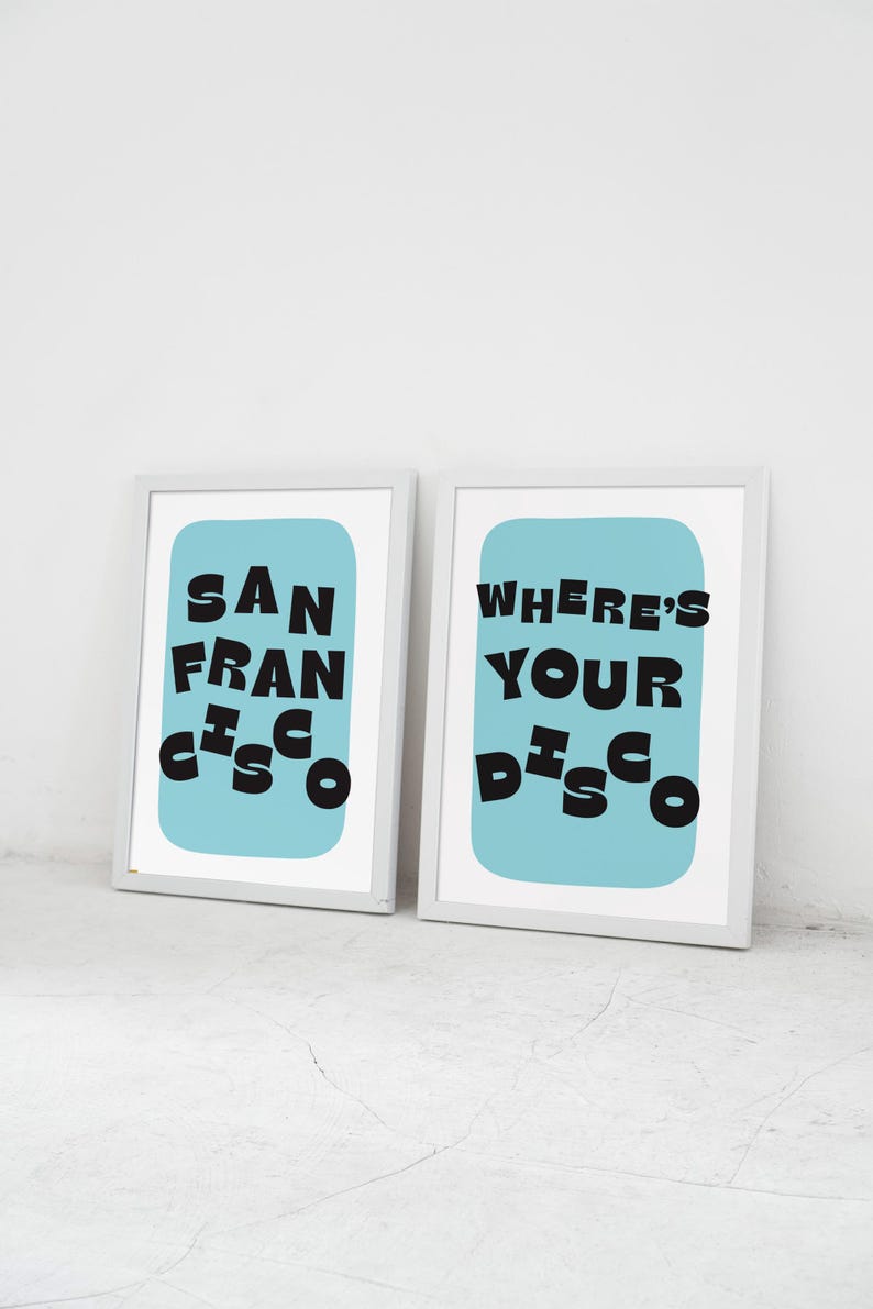 Puede incluir: Dos impresiones art&iacute;sticas enmarcadas. Una impresi&oacute;n dice "SAN FRANCISCO" en texto negro sobre un fondo azul claro. La otra impresi&oacute;n dice "WHERE'S YOUR DISCO" en texto negro sobre un fondo azul claro.