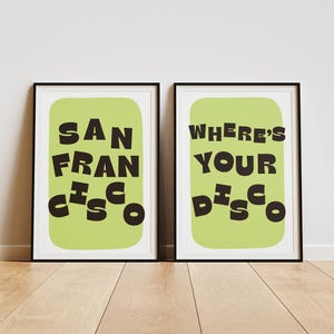 May include: Two framed art prints with black frames. One print says "SAN FRANCISCO" in black letters on a light green background. The other print says "WHERE'S YOUR DISCO" in black letters on a light green background.