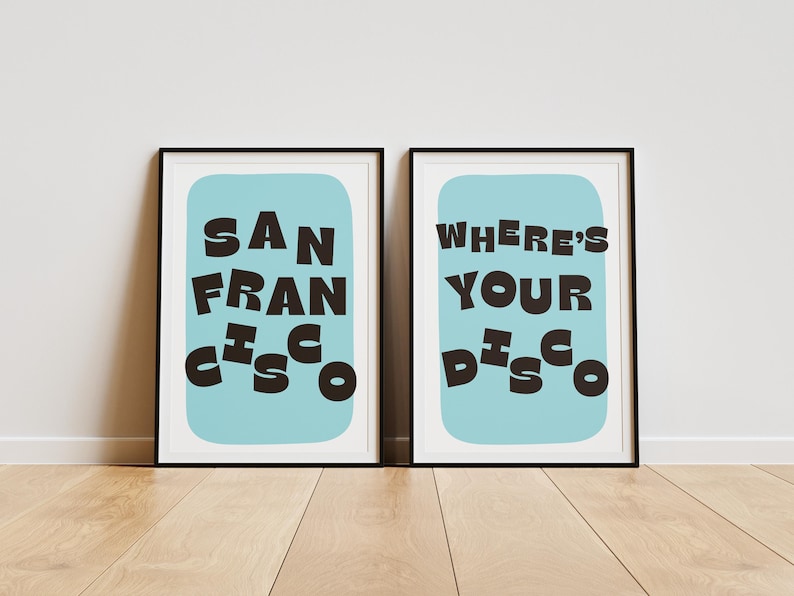 Puede incluir: Dos impresiones art&iacute;sticas enmarcadas con marcos negros. Una impresi&oacute;n dice "SAN FRANCISCO" en letras oscuras y marrones sobre un fondo azul claro. La otra impresi&oacute;n dice "WHERE'S YOUR DISCO" en un estilo similar.