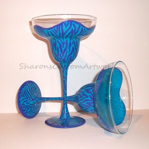 May include: Two blue and purple hand-painted margarita glasses with a zebra print design.