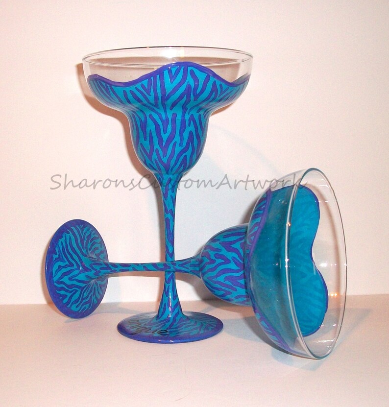 May include: Two blue and purple hand-painted margarita glasses with a zebra print design.
