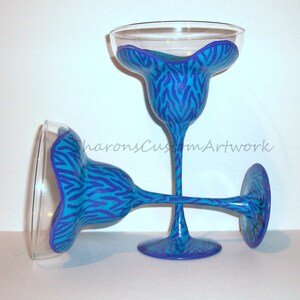 May include: Two blue and purple zebra print margarita glasses. The glasses are hand-painted with a blue and purple zebra print design.