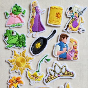 Könnte beinhalten: Drei cremefarbene Keramikbecher mit gesprenkelter Glasur. Jeder Becher zeigt ein handgemaltes Blumenmuster in Blau-, Grün- und Gelbtönen. Die Becher haben eine einfache, abgerundete Form und einen Griff.