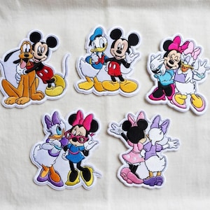 May include: Set of five embroidered patches featuring Disney characters Mickey Mouse, Minnie Mouse, Donald Duck, Daisy Duck, and Pluto. Each patch has a white border and depicts the characters in various poses, with vibrant colors.