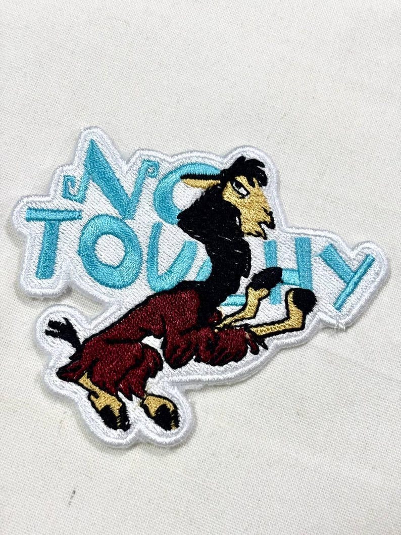 May include: Embroidered patch featuring a cartoon llama in shades of black, brown, and burgundy. The llama is set against a white background with the words "NO TOUCHY" in turquoise letters.