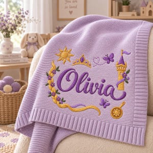 May include: A light purple knitted baby blanket featuring an embroidered design with the name Olivia in dark purple script. The embroidery includes a golden sun, a crown, a tall tower, a frying pan, and purple butterflies with yellow braided hair.
