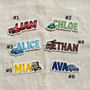 Puede incluir: Parches de nombres bordados con nombres como Liam, Chloe, Alice, Ethan, Mia y Ava. Cada parche incluye una ilustraci&oacute;n de un coche de dibujos animados. Los parches tienen un borde blanco y est&aacute;n sobre un fondo beige.