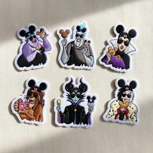 Könnte beinhalten: Set aus sechs gestickten Aufnähern mit Disney-Bösewichten mit Mickey Mouse Ohren. Jeder Aufnäher zeigt einen Charakter, der eine Leckerei hält. Die Aufnäher haben einen weißen Rand.