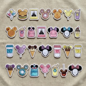 Può includere: Una collezione di toppe ricamate con vari disegni a tema Disney. Le toppe includono teste di Topolino, articoli alimentari come hamburger e coni gelato e immagini del castello Disney. Le toppe sono in vari colori.