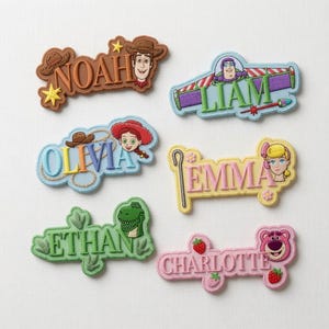 Puede incluir: Seis parches bordados con nombres y personajes de Toy Story. Los parches muestran los nombres Noah, Liam, Olivia, Emma, Ethan y Charlotte, decorados con motivos específicos como sombreros de vaquero, alas de guardián espacial, lazos, cayados, huellas de dinosaurio y fresas.