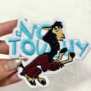 May include: Embroidered patch featuring a cartoon llama in a dynamic pose. The llama is primarily burgundy with black and yellow accents. The patch has the words "NO TOUCHY" in light blue letters with a white border. This patch is suitable for jackets, bags, or other fabric items.