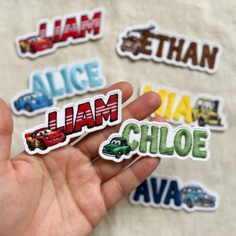 Puede incluir: Parches bordados con nombres e ilustraciones de coches. Los nombres "Liam", "Ethan", "Alice", "Mia", "Chloe" y "Ava" se muestran en varios colores. Los parches son rojos, azules, verdes y amarillos.