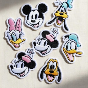Pode incluir: Patches bordados com personagens de desenhos animados populares, incluindo Mickey Mouse, Minnie Mouse, Pato Donald, Margarida, Pateta e Pluto. Cada patch tem uma borda branca e mostra cores vibrantes e expressões faciais detalhadas.