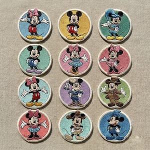 May include: A set of twelve embroidered patches showcasing Mickey and Minnie Mouse in various designs. Each circular patch has a light-coloured border and a vibrant background. Mickey and Minnie are depicted in different outfits and poses.