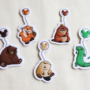 May include: Embroidered patches featuring cartoon animals: a bear, beaver, lizard, and others. Each patch has a white border and a Mickey Mouse-shaped balloon. The bear is brown, the beaver is orange, and the lizard is green.