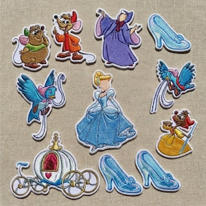 Peut inclure: Écussons brodés représentant des personnages et des éléments d'un conte de fées. Comprend Cendrillon, des souris, des oiseaux, un carrosse, des pantoufles de verre et la bonne fée. Les écussons sont dans les tons de bleu, jaune, marron et violet.