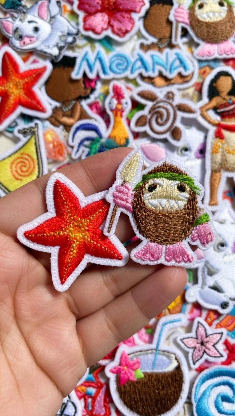 May include: Embroidered patches featuring characters and elements from the animated film "Moana." Includes a red starfish, a coconut character with a spear, and the film's title. Patches have white borders and are on a white background.