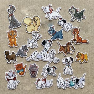 Puede incluir: Colección de parches bordados con varios perros y gatos de dibujos animados. Los parches muestran una variedad de razas y personajes en diferentes poses, con un fondo neutro.