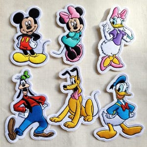 May include: Set of six embroidered patches featuring beloved cartoon characters: Mickey Mouse, Minnie Mouse, Daisy Duck, Goofy, Pluto, and Donald Duck. Each patch has a white border and vibrant colors, perfect for decorating clothing or accessories.