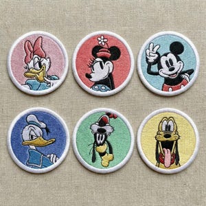 May include: Embroidered patches featuring Disney characters Daisy Duck, Minnie Mouse, Mickey Mouse, Donald Duck, Goofy, and Pluto. Each patch is circular with a white border and a colourful background, showcasing the characters' faces.