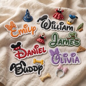 Puede incluir: Una colección de parches bordados con los nombres Emily, William, Daniel, James, Olivia y Buddy. Cada parche incorpora iconos temáticos de personajes como lazos, orejas y huesos, con detalles de telaraña integrados en las letras.