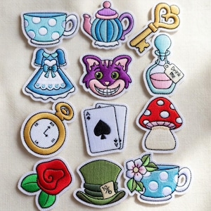 May include: A collection of embroidered patches featuring whimsical designs from Alice in Wonderland. Includes a teacup, teapot, key, dress, Cheshire Cat, potion bottle, pocket watch, playing cards, mushroom, rose, hat, and a teacup with flowers.