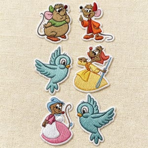 Può includere: Toppe ricamate con personaggi delle fiabe. Il set comprende due topi in costume, due uccelli blu e due personaggi in abito. Le toppe hanno un bordo bianco e sono su sfondo beige.